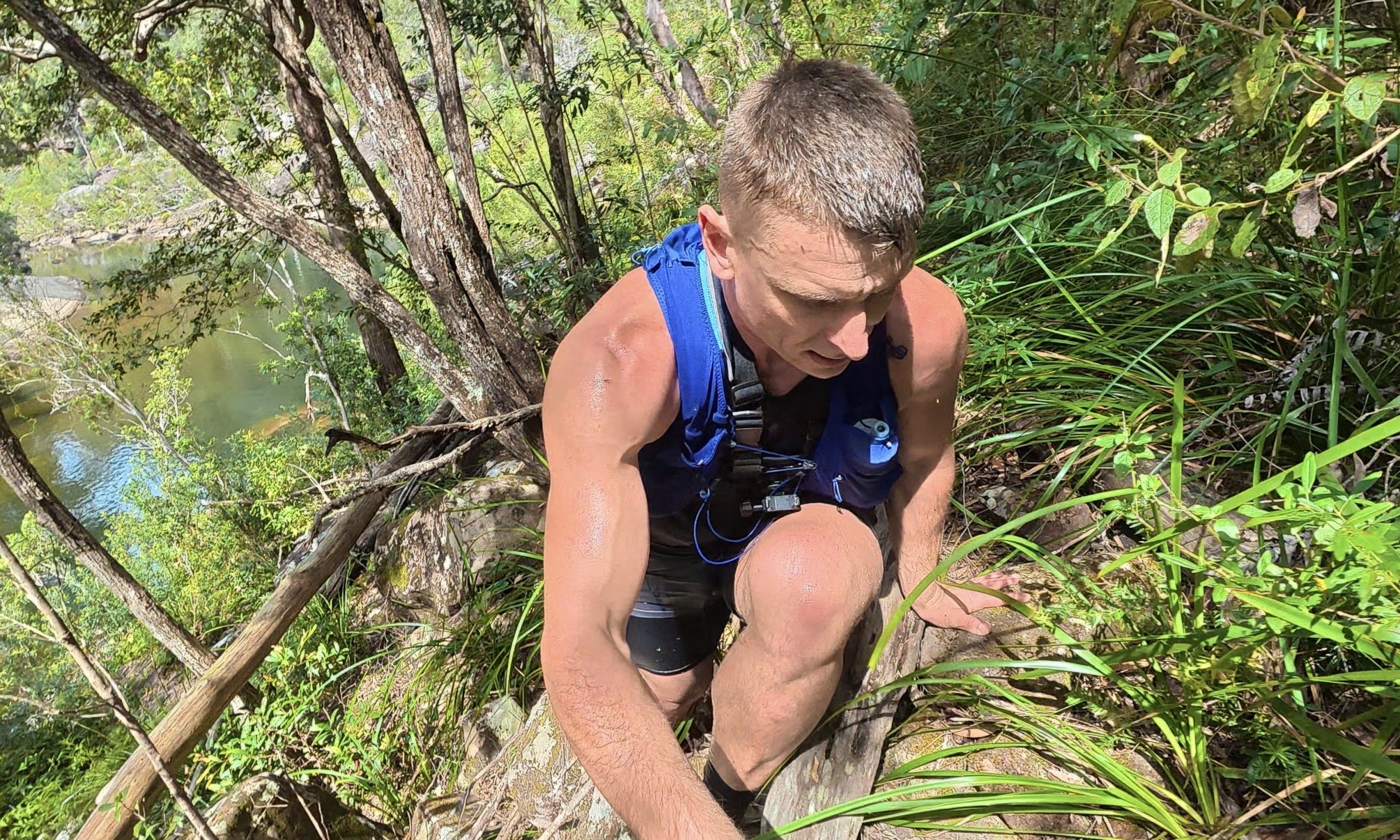 Nathan climbing up a steep, overgrown slope using his hands