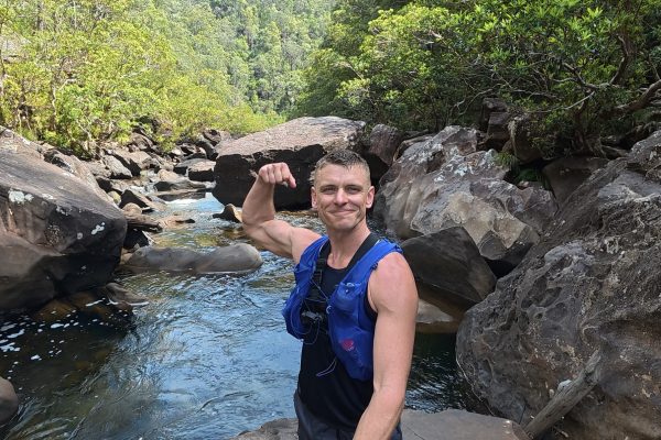 Nathan smiling and flexing beside a rocky pool on the Grose River