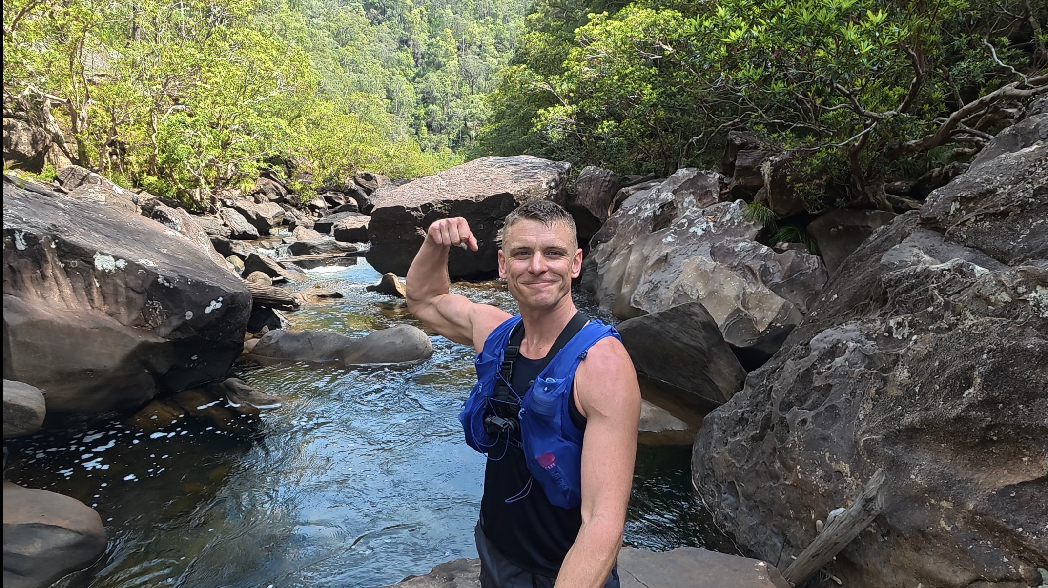 Nathan smiling and flexing beside a rocky pool on the Grose River